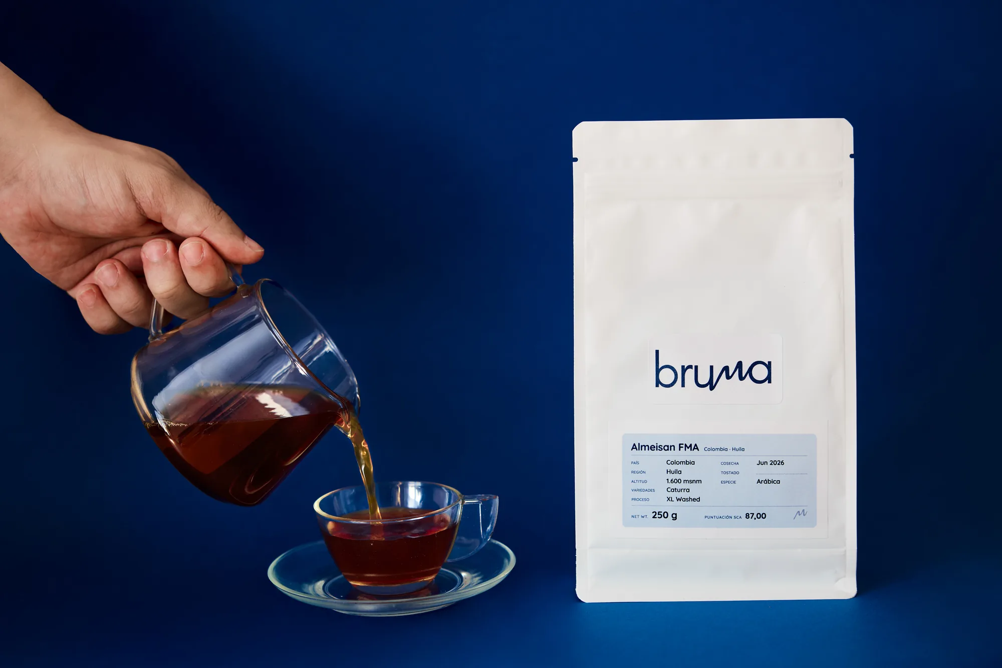 Sirviendo café recién preparado en una taza junto a una bolsa de café Bruma